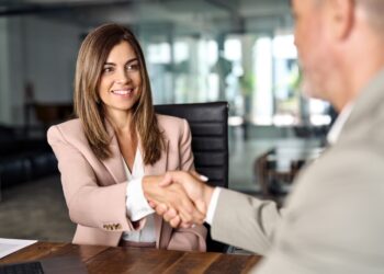 A smiling middle-aged new employee is successfully onboarded by a corporate human resources executive