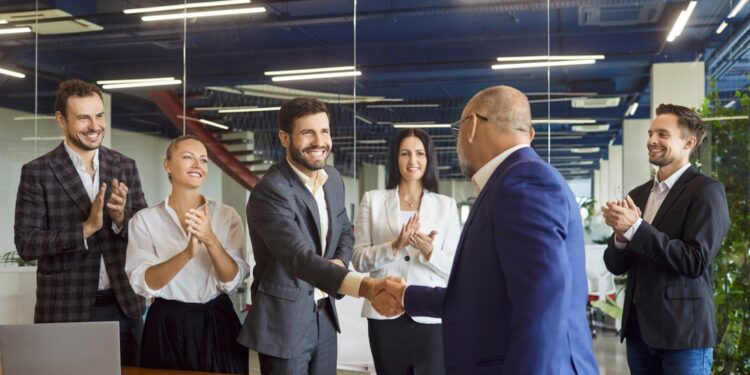 Corporate executives celebrate a deal with a handshake and applause. Picture for illustrative purposes only.
